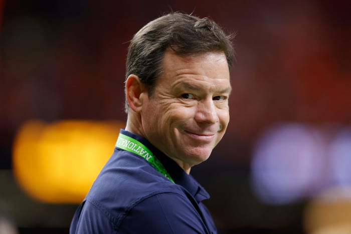 Jim Mora smirks at the camera while on the sidelines during a game.