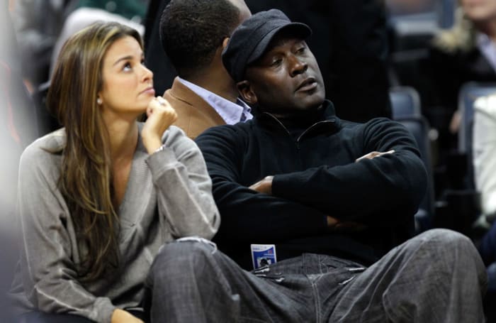 Michael Jordan and his wife seated at the edge of the court.