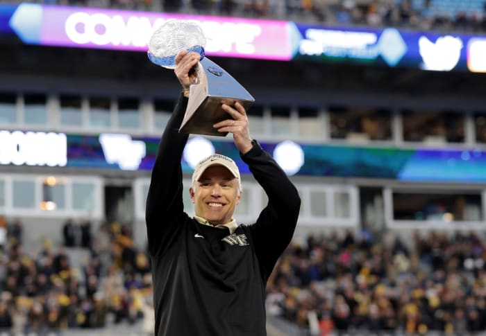 Wake Forest football coach Dave Clawson raising a trophy.
