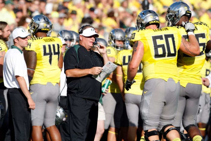 Chip Kelly talks to two players during a game.