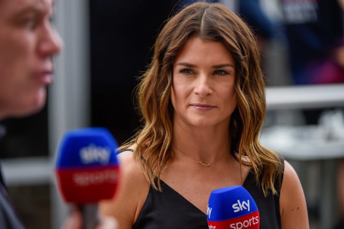 Danica Patrick holding a microphone at a F1 race.