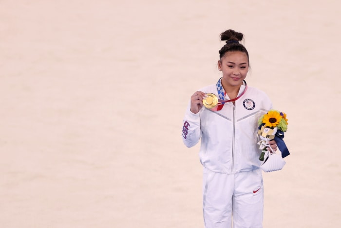 Suni Lee showcases her gold medal.