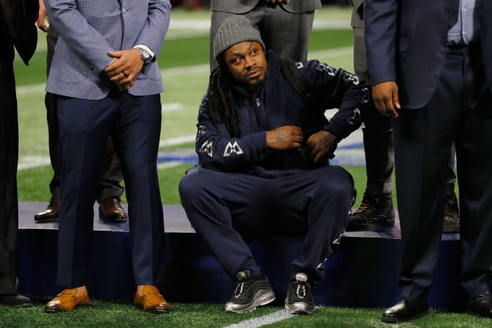 Marshawn Lynch sitting on the football field.