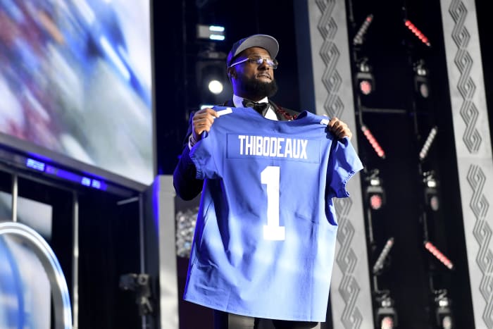 A picture of Kayvon Thibodeaux holding up a No. 1 Giants jersey on stage after being drafted.