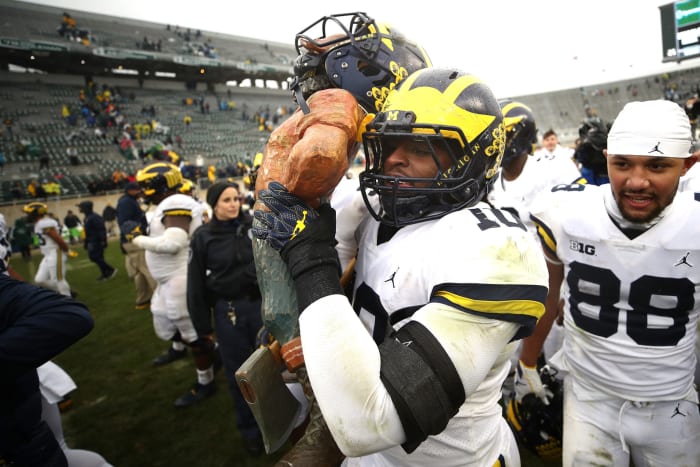 Devin Bush carries the Paul Bunyan trophy.