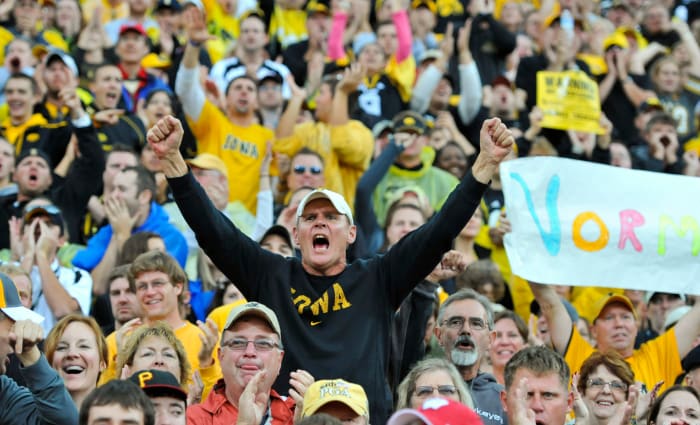 An Iowa Hawkeyes fan celebrating in the stands during a football game.