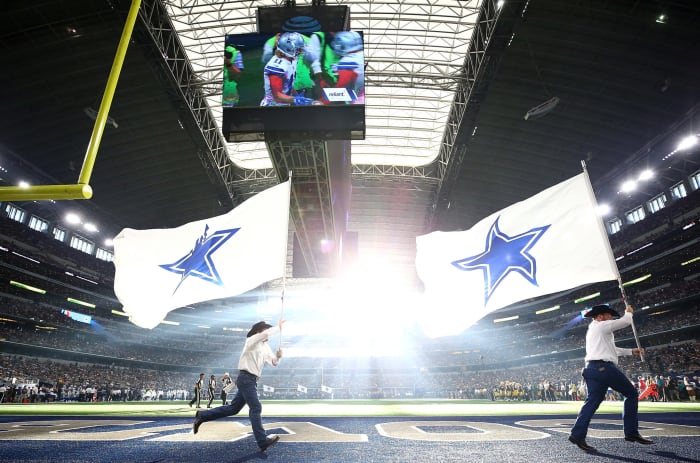 Cowboys cheerleaders running with Cowboys fields.