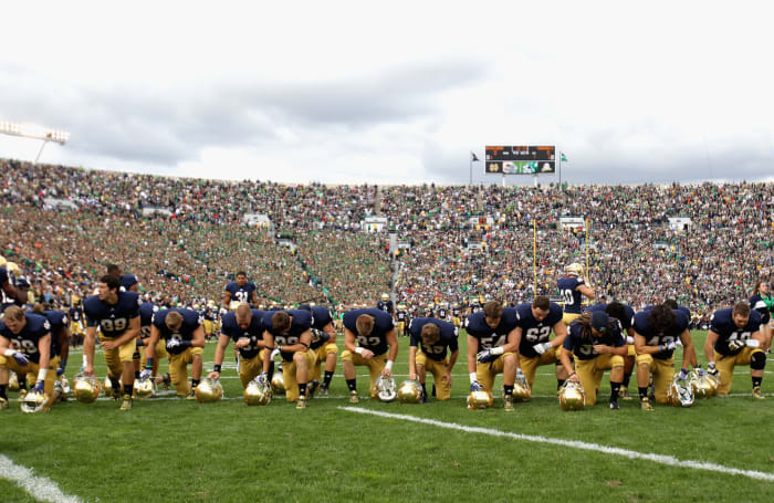 Notre Dame players kneeling on the sideline.