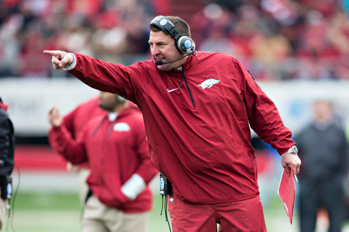 Bret Bielema pointing while wearing a red Arkansas jumpsuit.