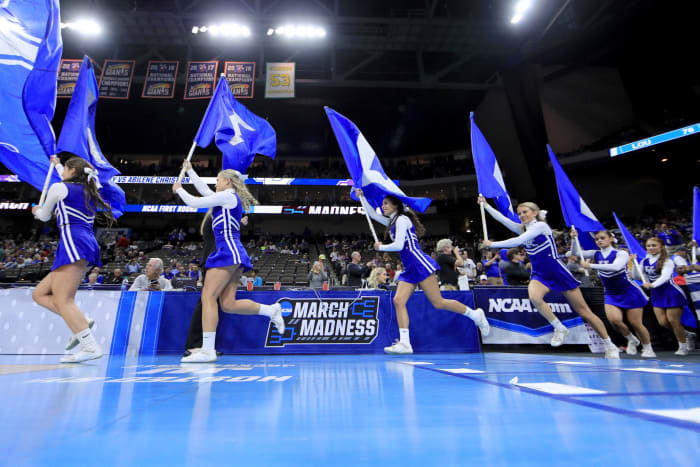 Kentucky Wildcats cheerleaders running onto the basketball court.