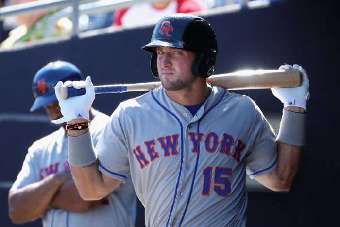 Tim Tebow holding a baseball bat behind his back.