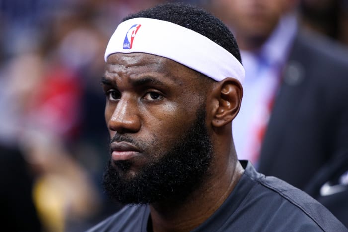 LeBron James sits on the bench during a preseason game.