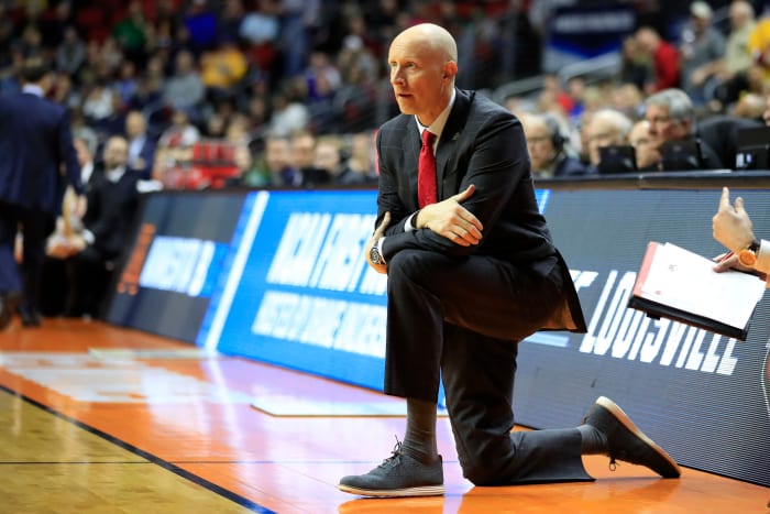 Louisville Cardinals head coach Chris Mack kneeling on the sideline during a game.