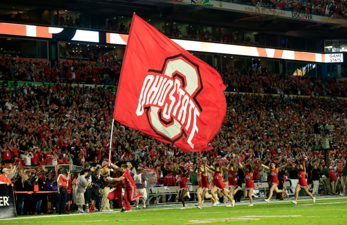 An Ohio State Buckeyes cheerleader running with a flag.