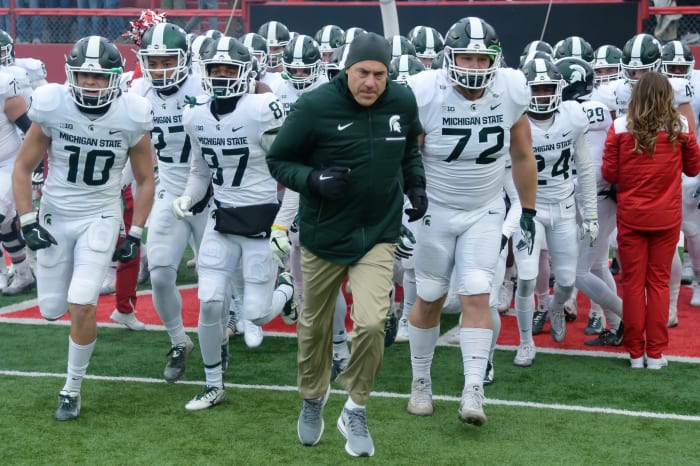 Mark Dantonio and the Michigan State football team running onto the field.
