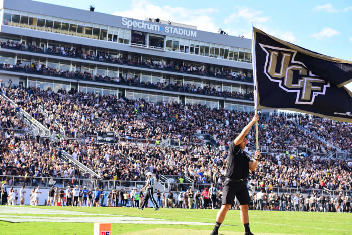 A man holding a UCF flag in the air.