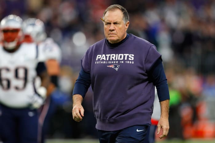Bill Belichick walking on the field in Patriots gear.