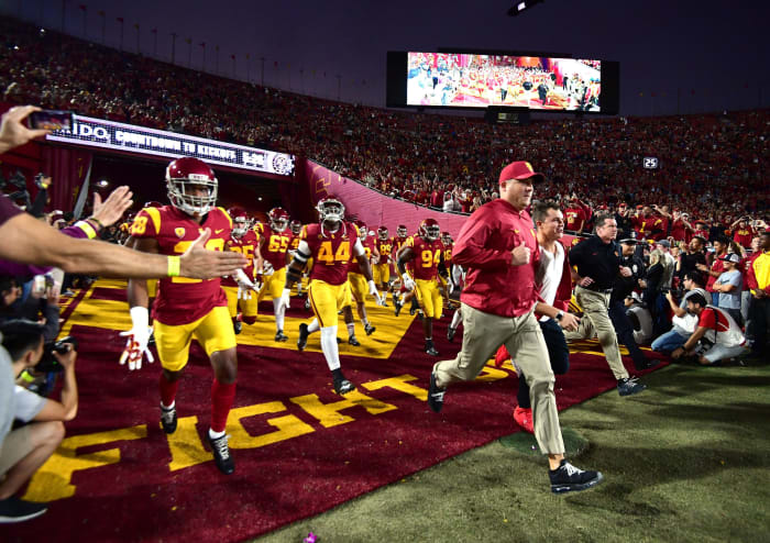 Clay Helton running onto the field with the USC football team.