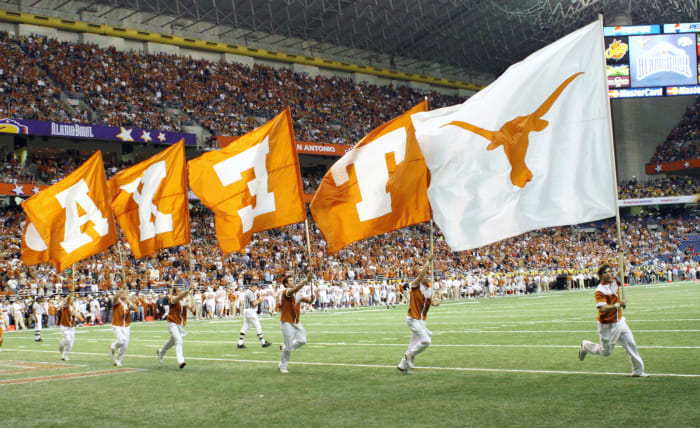 Texas Longhorns cheerleaders running with team flags.