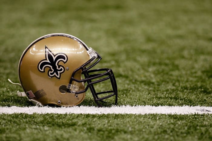 A closeup of a New Orleans Saints helmet on the football field.