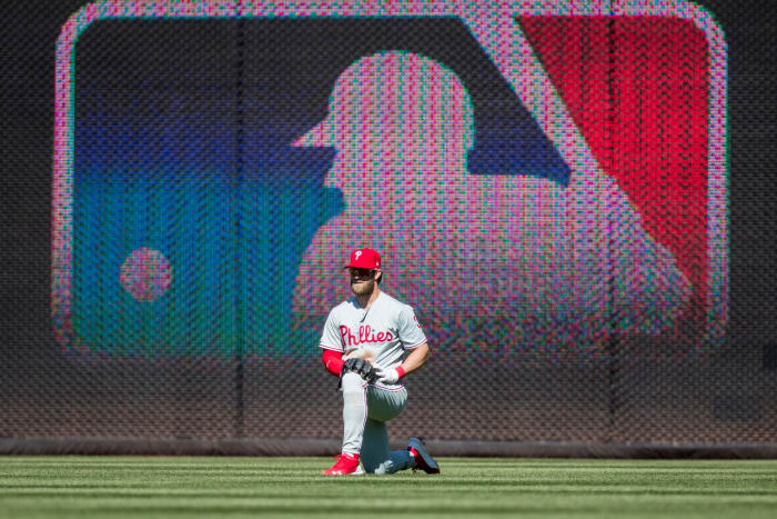 Bryce Harper kneeling on one knee in the outfield.