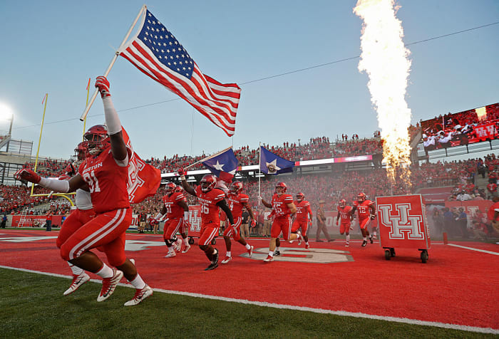 The Houston Cougars carrying the American flag and UH flag enter the field before playing against the Rice Owls sat TDECU Stadium.