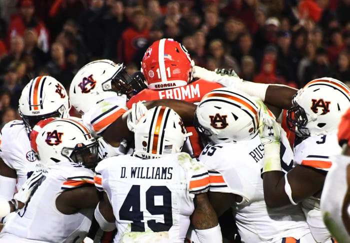 Auburn football players tackling Jake Fromm during an SEC college football rivalry game.