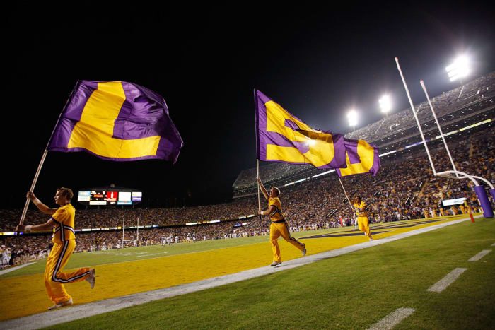LSU cheerleaders run around the field with flags.
