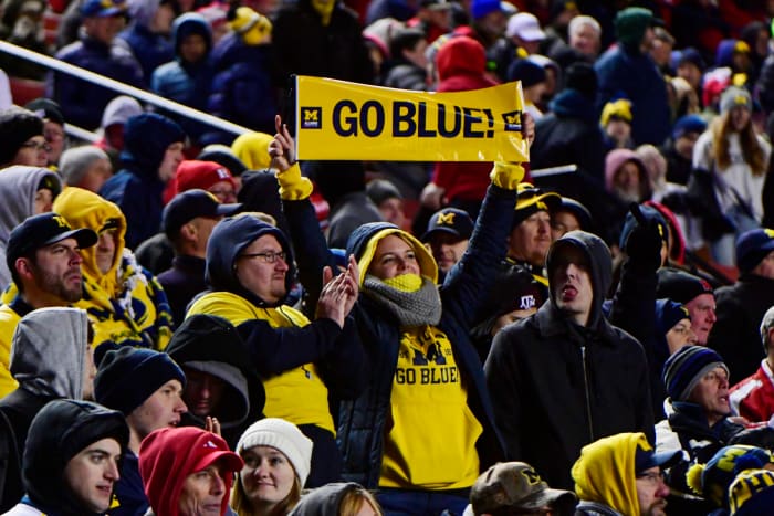 A Michigan fan holding up a sign that says "Go Blue" during a football game.