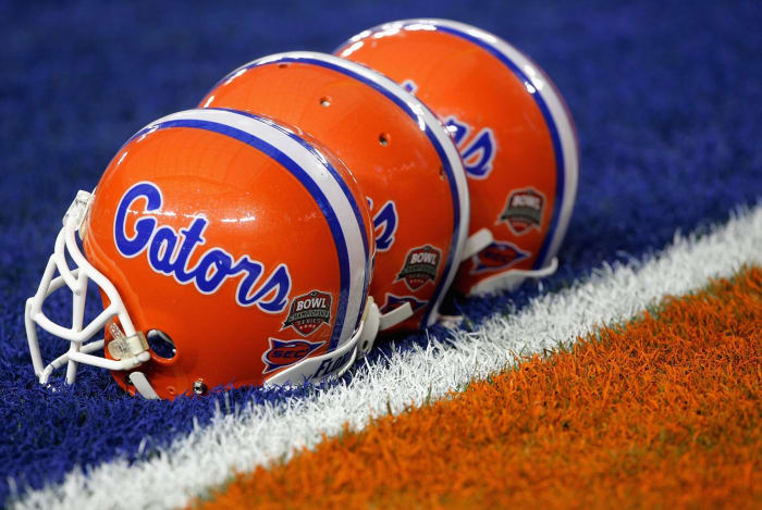 Three Florida Gators football helmets on the field.