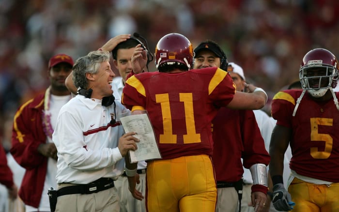Matt Leinart hugging Steve Sarkisian and Pete Carroll during a college football game.