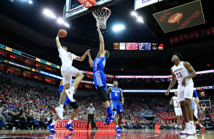 Louisville and Kentucky basketball players meet at the rim.