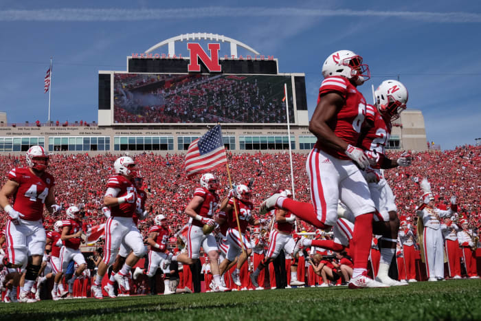 Nebraska football players run onto the field.