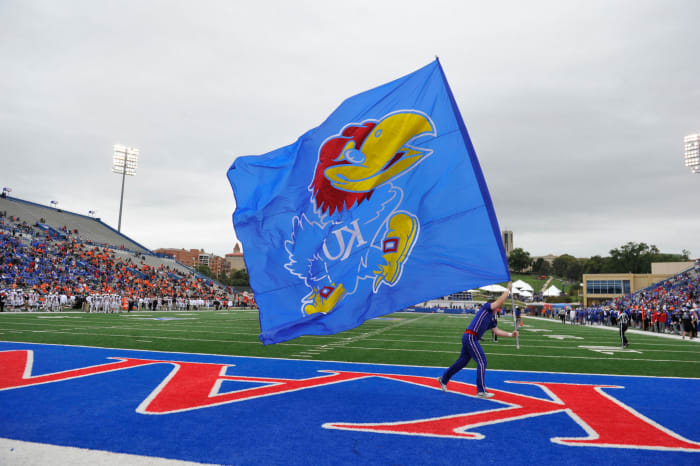 Kansas cheerleader runs with a Jayhawk flag during football game.