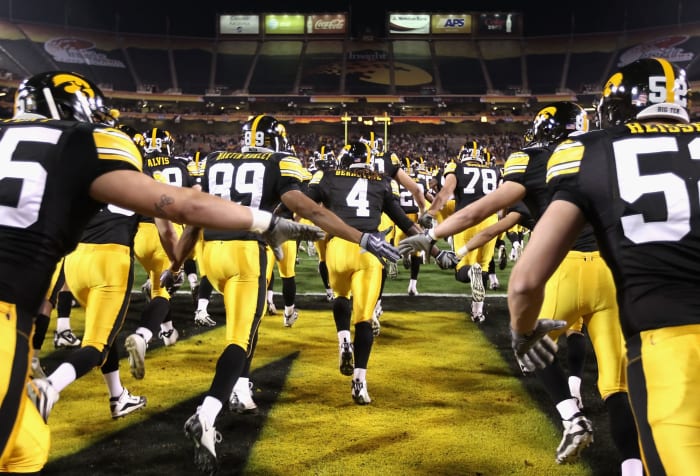 Iowa football players run onto the field.