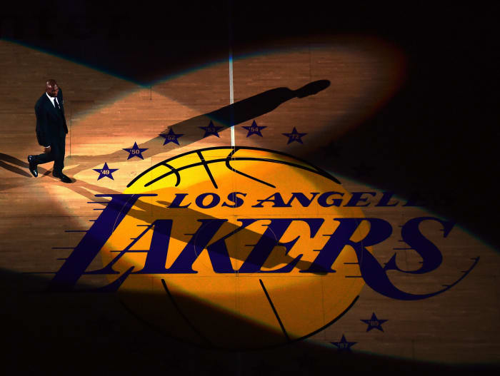 Kobe Bryant wearing a suit while standing at center court of the Staples center.