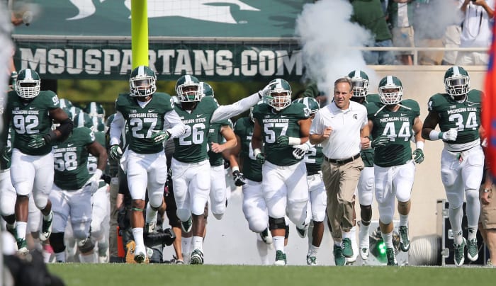 Mark Dantonio and the Michigan State football team running onto the field.