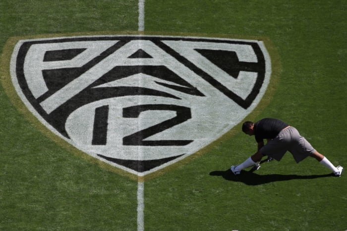 A member of Cals football team stretching next to a Pac-12 football logo.