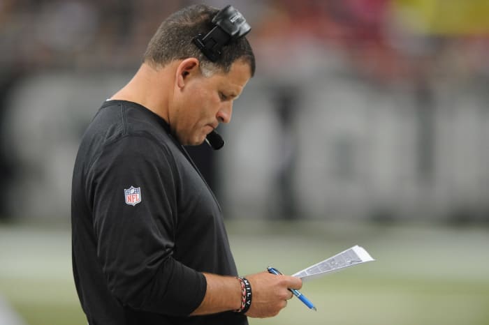 Greg Schiano staring down at a play sheet.