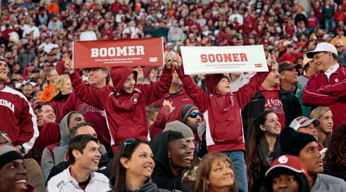 Two Oklahoma Sooner fans holding up signs during a football game.