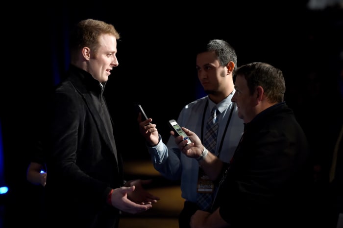 Greg McElroy speaks with reporters at an event.