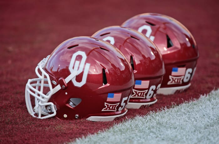 A closeup of three Oklahoma Sooners football helmets on the field before a football game.