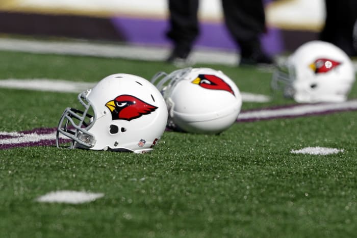 Three Arizona Cardinals helmets sitting on the field.