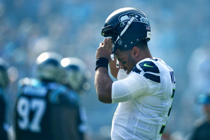 A closeup of Russell Wilson putting his Seattle Seahawks hat on.