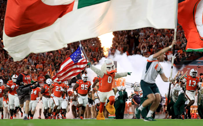 Miami college football players run onto the field before a game.