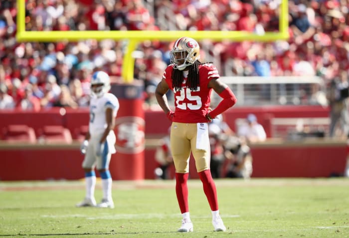 Richard Sherman standing on the field with his arms on his hips during a 49ers game.
