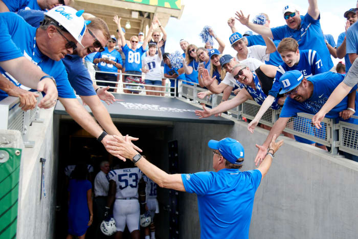 David Cutcliffe high fives fans after Duke win.