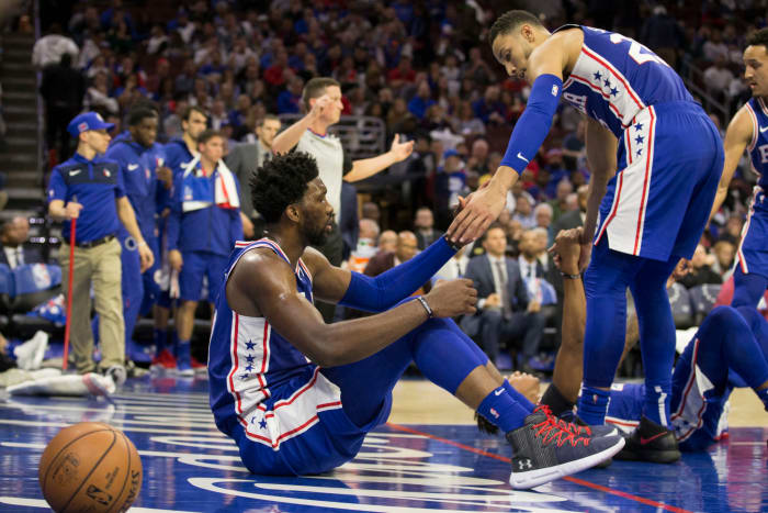 Philadelphia 76ers star Ben Simmons helping Joel Embiid stand up.