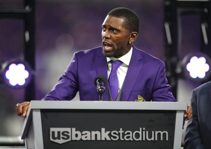 Randy Moss speaking at a podium.