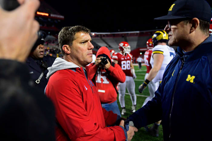 Jim Harbaugh shaking hands with Chris Ash following a football game.